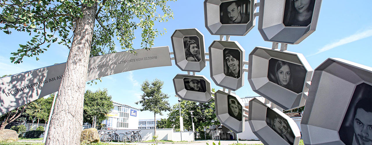 Ein Ginko Baum umgeben von einem überdimensionalen Ring mit den Portraits der neun getöteten Menschen.