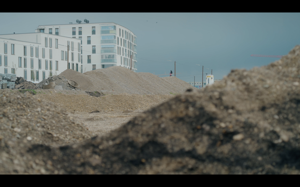 Das Bild zeigt die Baustelle mit Erdaushub und bereits fertige Wohnblocks