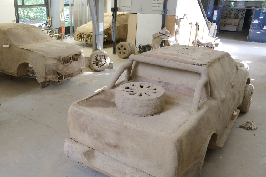 Ansicht der fertiggestellten Lehmskulptur in Form eines SUV im Atelier