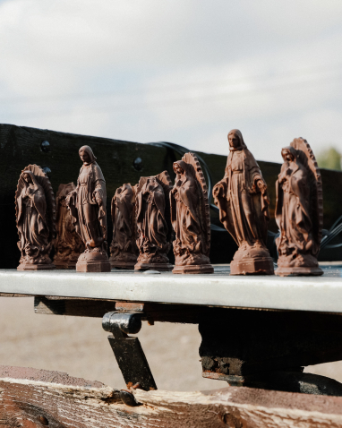 Several small figures of saints made of brown material stand in a row.