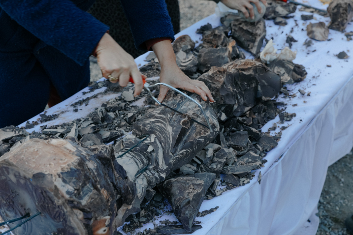 Person sawing a broken sculpture on a table covered with white cloths.